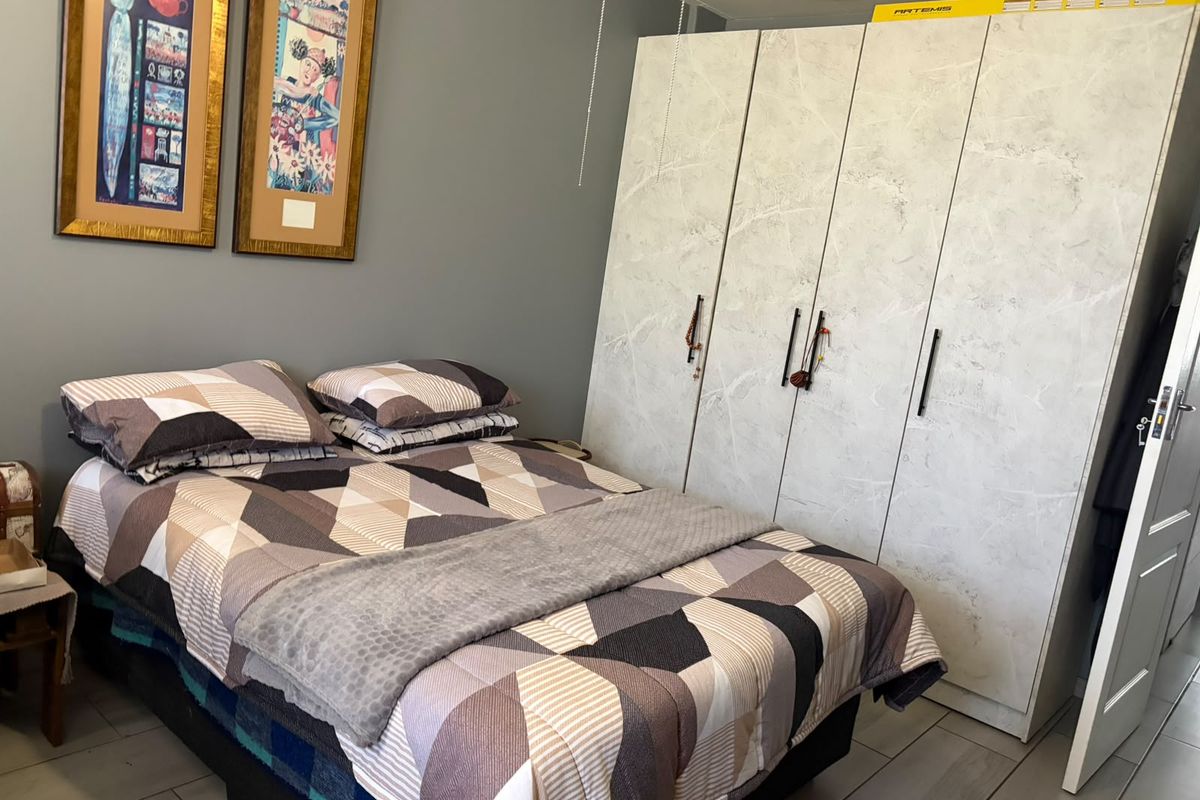 A bedroom featuring tiled flooring and a large, modern built-in wardrobe with a marble-effect finish.