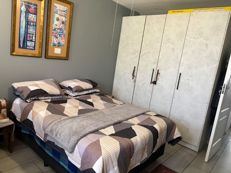 A bedroom featuring tiled flooring and a large, modern built-in wardrobe with a marble-effect finish.
