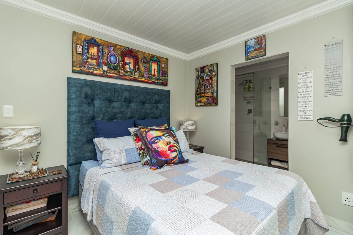 A well-maintained bedroom featuring crown molding, a tongue and groove ceiling, and an integrated en-suite bathroom with a glass shower enclosure.