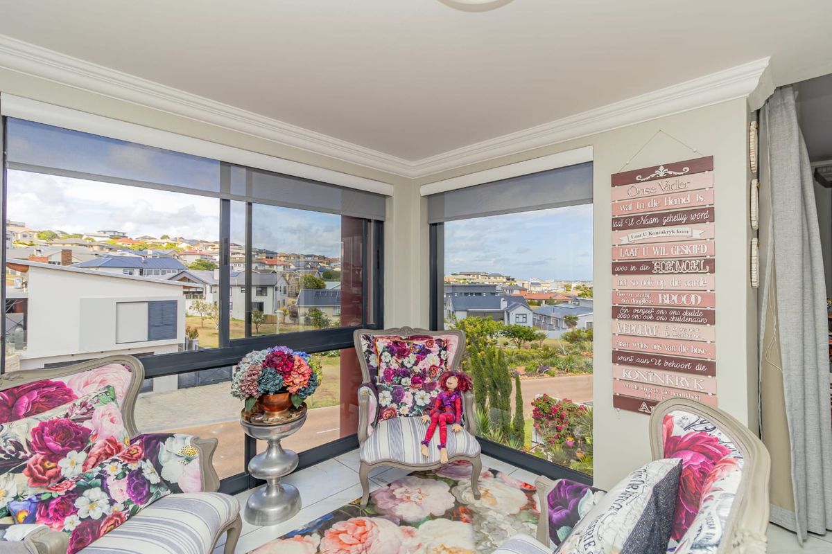 A bright living area featuring large windows with expansive neighbourhood views, tiled flooring, and elegant crown molding.
