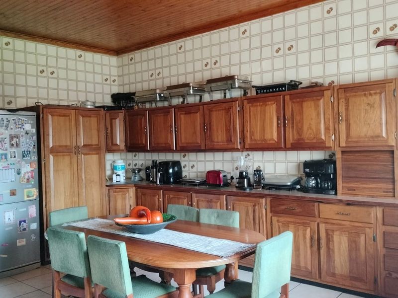 A traditional kitchen featuring extensive wooden cabinetry, a tiled backsplash, and a warm wooden ceiling, offering a classic aesthetic with functional storage space.