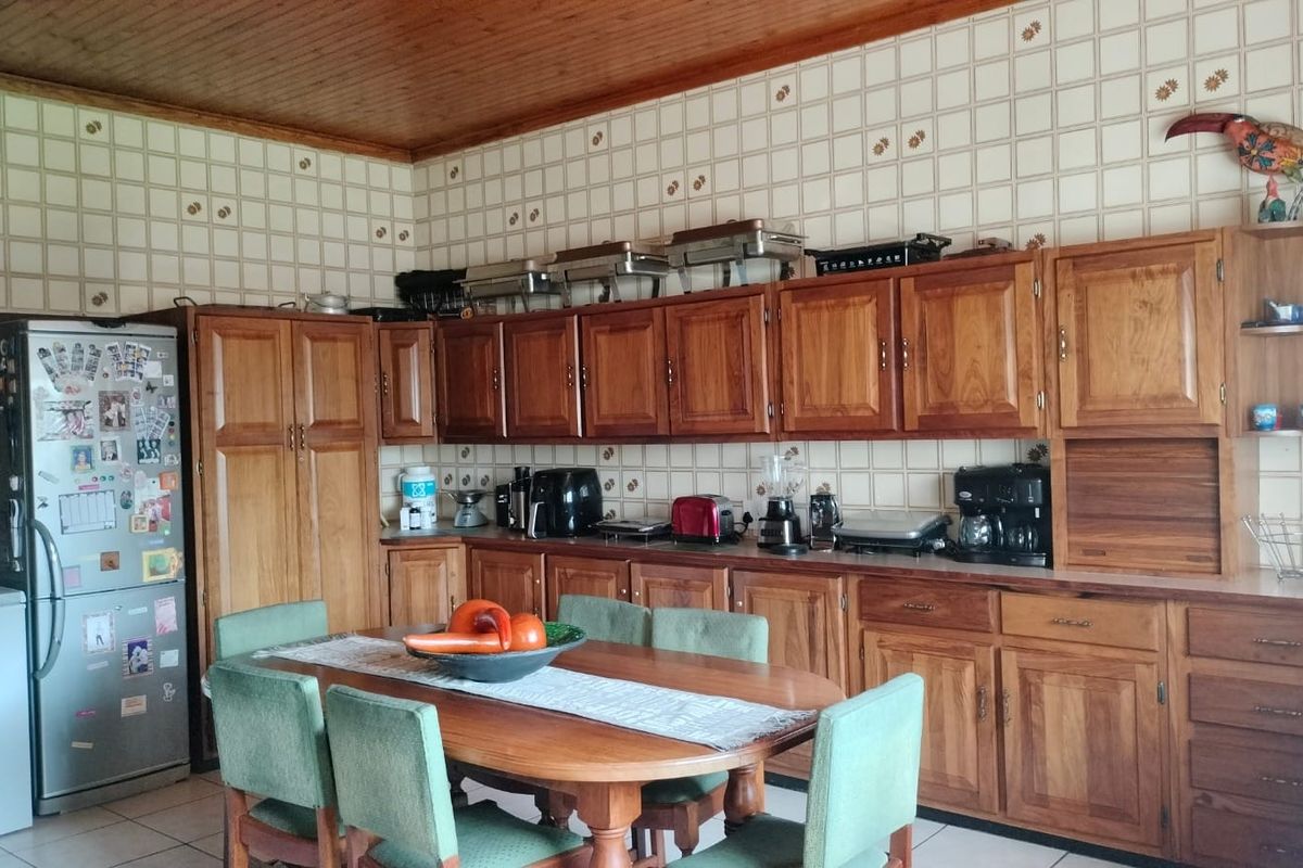 A traditional kitchen featuring extensive wooden cabinetry, a tiled backsplash, and a warm wooden ceiling, offering a classic aesthetic with functional storage space.