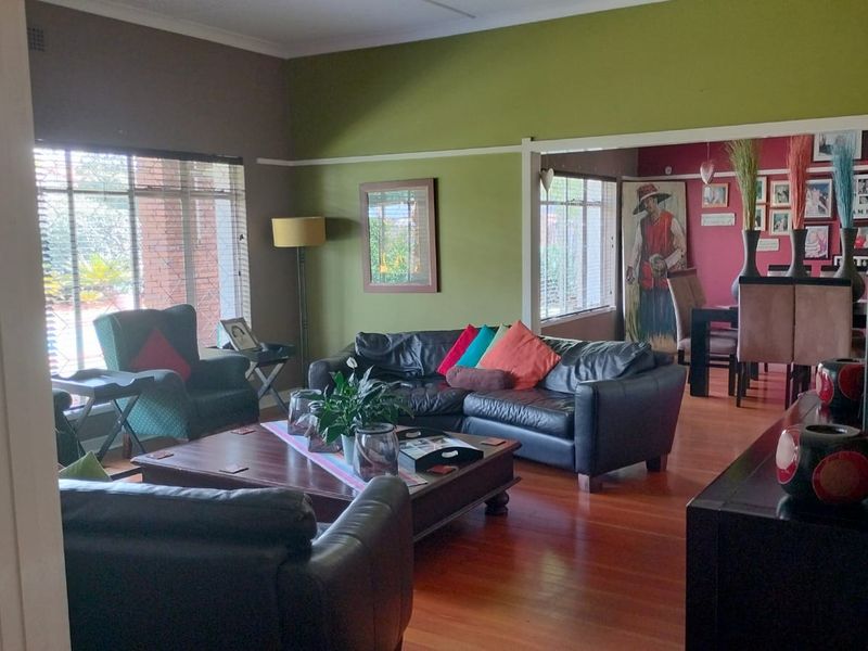Spacious open-plan living and dining area featuring warm hardwood flooring, large windows for natural light, and classic picture rail detailing.