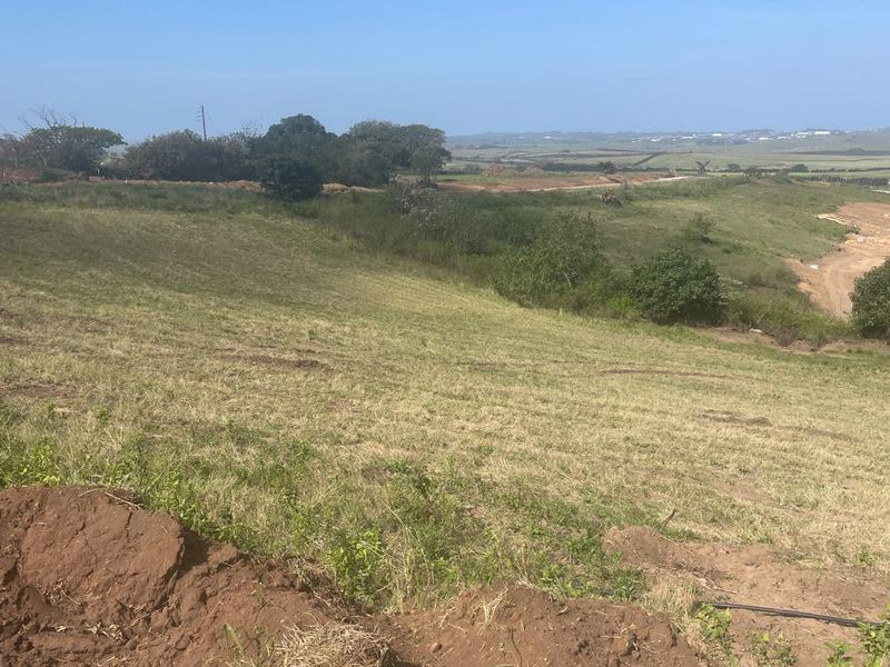 A wide-angle view of the vacant residential land, showcasing the natural sloped topography and surrounding landscape.