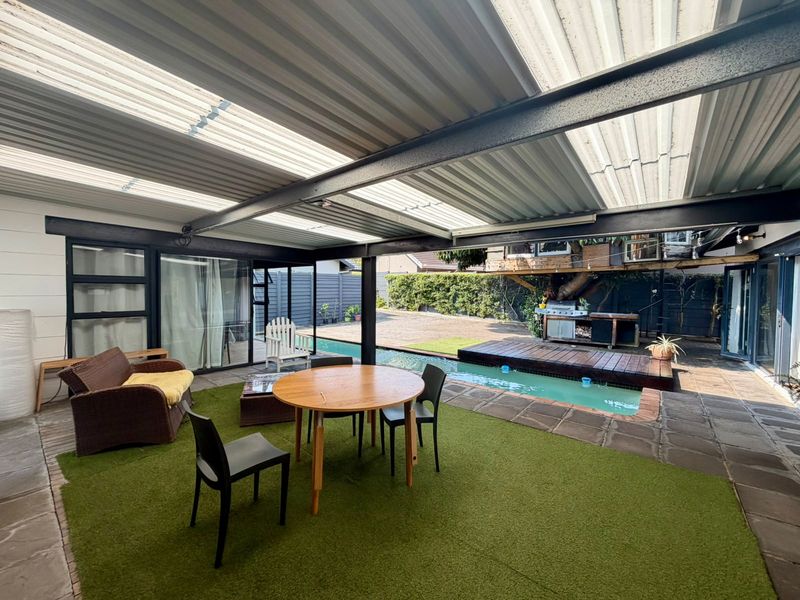 Covered outdoor patio area featuring a swimming pool, timber decking, and direct access to the home through sliding glass doors.