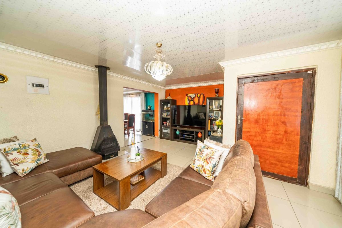 Spacious living room featuring a freestanding fireplace, tiled flooring, and coved ceiling details, providing a comfortable and functional family living space.