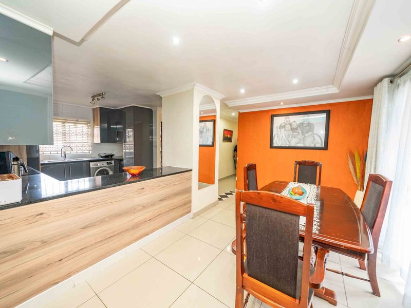 Open-plan kitchen and dining area featuring modern cabinetry, granite countertops, tiled flooring, and direct access to the outdoor space via sliding doors.