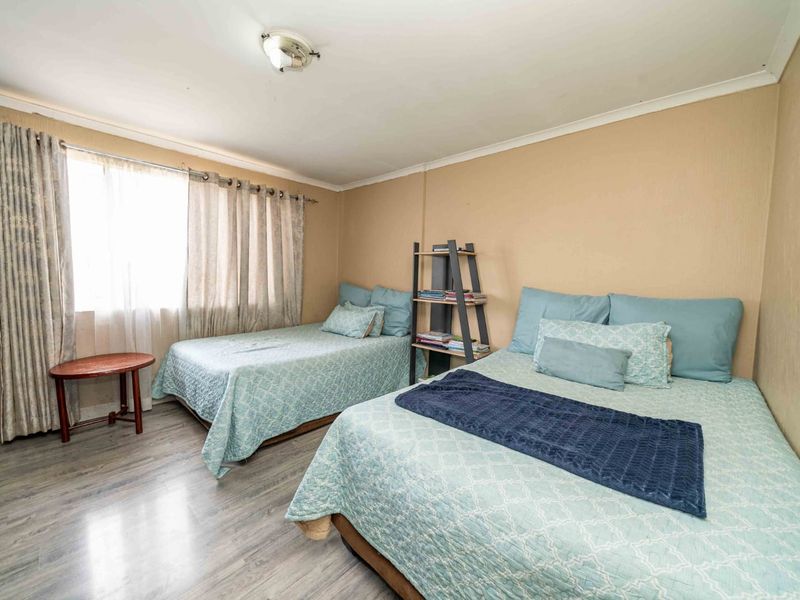 A functional bedroom featuring laminate flooring, neutral wall tones, and a built-in cupboard, providing a comfortable and practical living space.