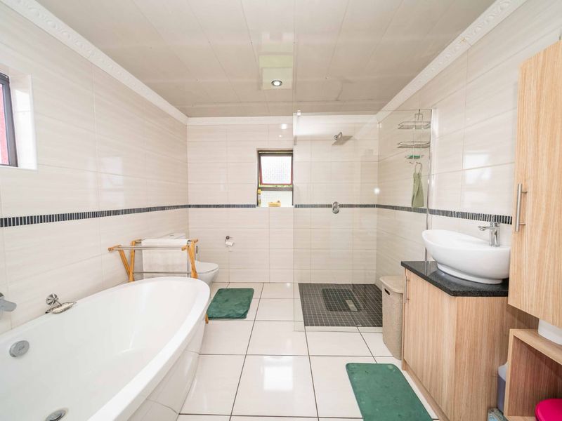 Modern bathroom featuring a freestanding bathtub, a spacious walk-in shower with glass screen, and a vanity unit with a vessel sink.