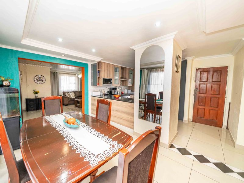 Open plan dining and kitchen area featuring tiled floors, recessed lighting, and a functional kitchen layout with wood-finish cabinetry.
