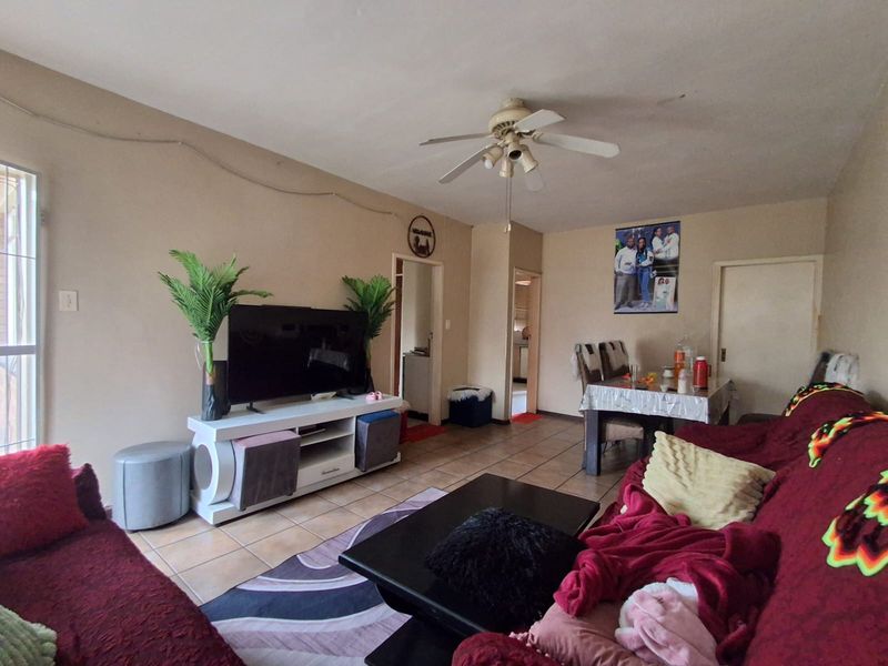 Open-plan living and dining area featuring tiled flooring and a ceiling fan, with access to adjacent rooms.