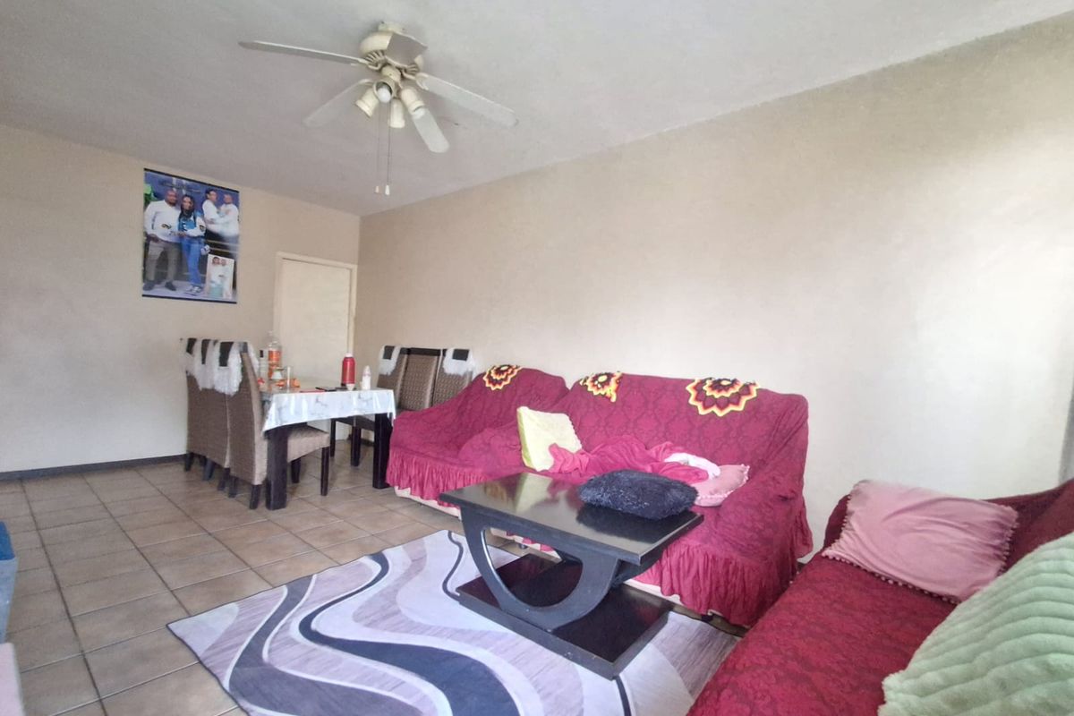 A living room area featuring tiled flooring and a ceiling fan, providing a functional space for relaxation.
