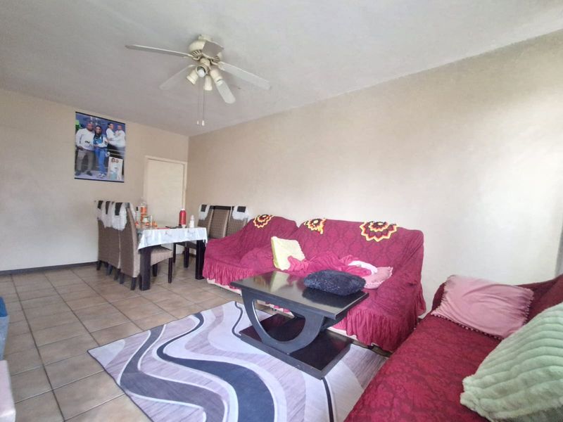 A living room area featuring tiled flooring and a ceiling fan, providing a functional space for relaxation.