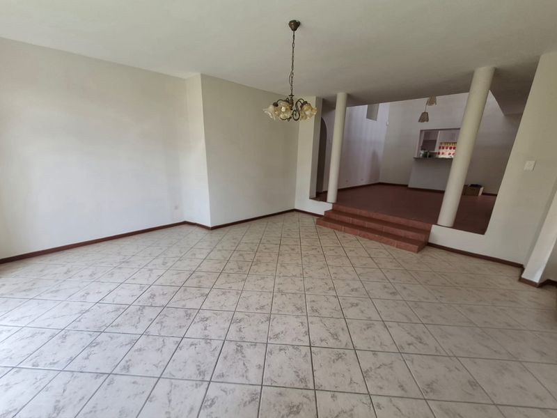 Spacious open-plan living area featuring tiled flooring, a raised platform section, and structural columns, offering a versatile layout for dining and lounge arrangements.