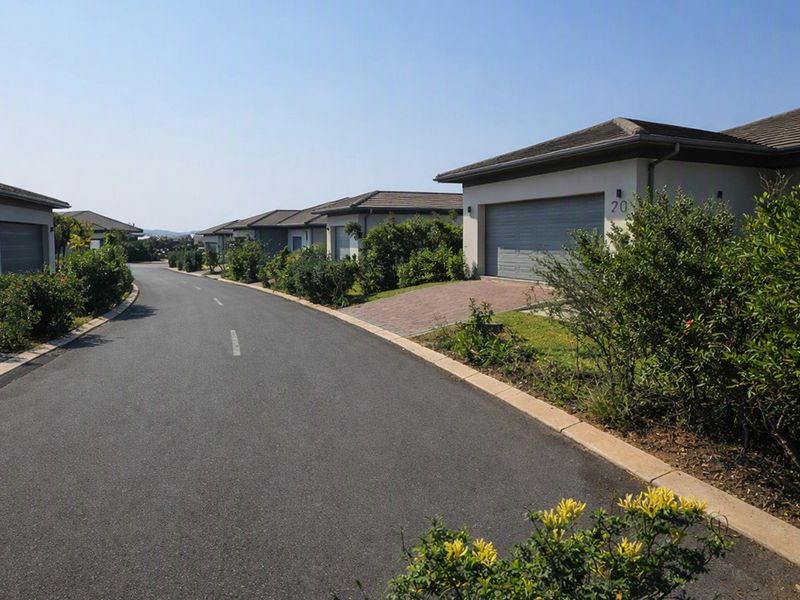 A view of a residential street within a housing estate, featuring paved driveways, garages, and well-maintained landscaped gardens.