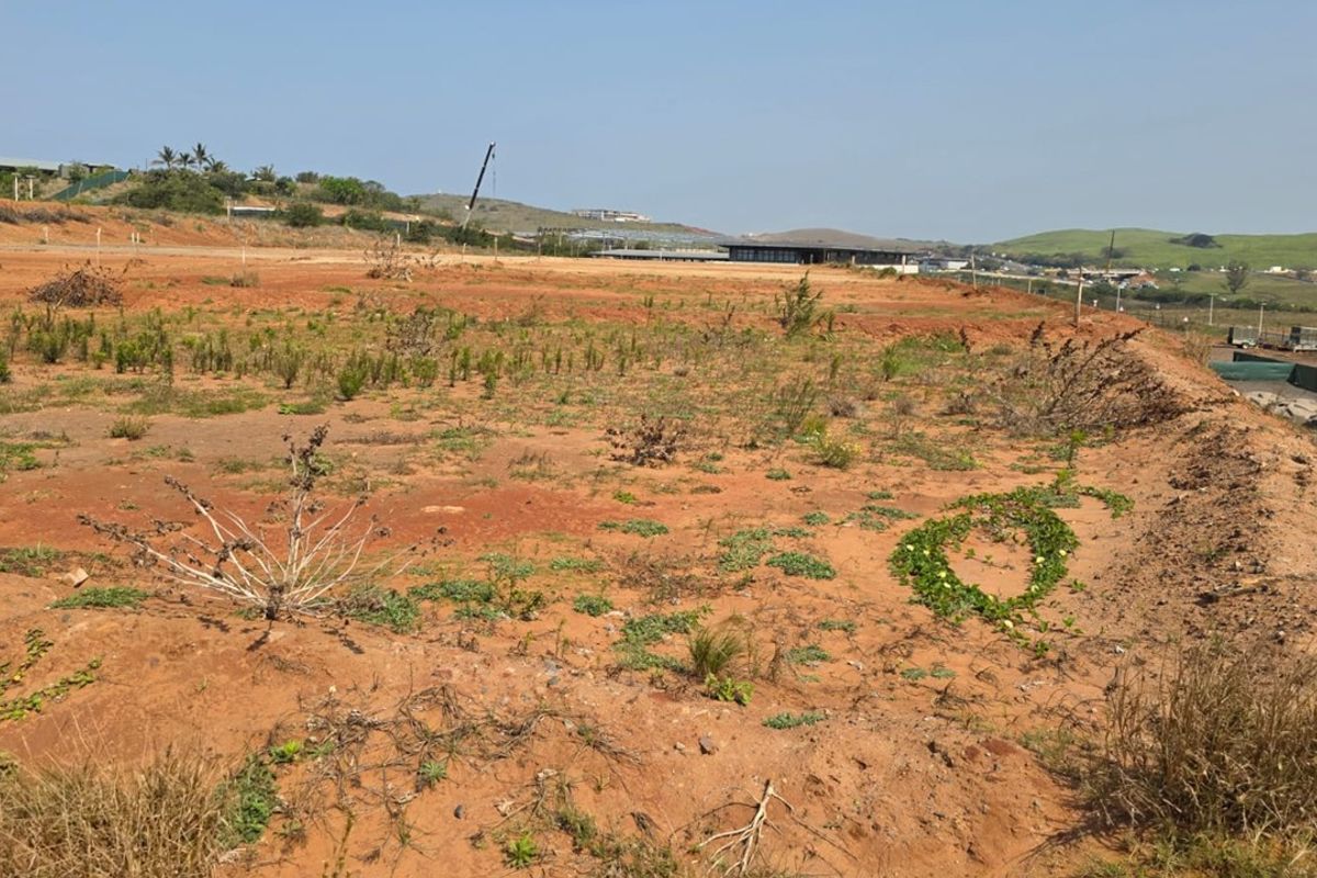 A wide-angle view of a vacant residential plot featuring natural terrain and earthworks, ready for future development.