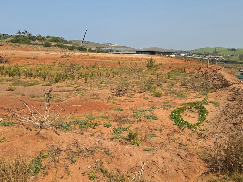 A wide-angle view of a vacant residential plot featuring natural terrain and earthworks, ready for future development.