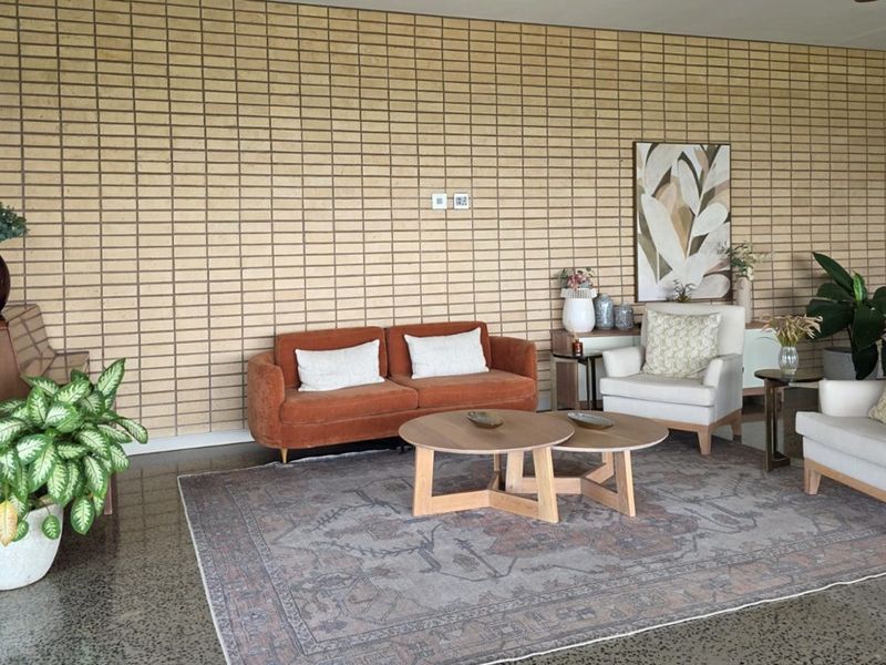 A spacious living area featuring a textured exposed brick feature wall and polished concrete flooring, creating a modern and industrial aesthetic.