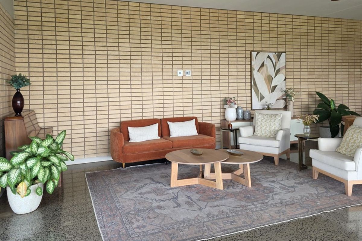 A spacious living area featuring a textured exposed brick feature wall and polished concrete flooring, creating a modern and industrial aesthetic.