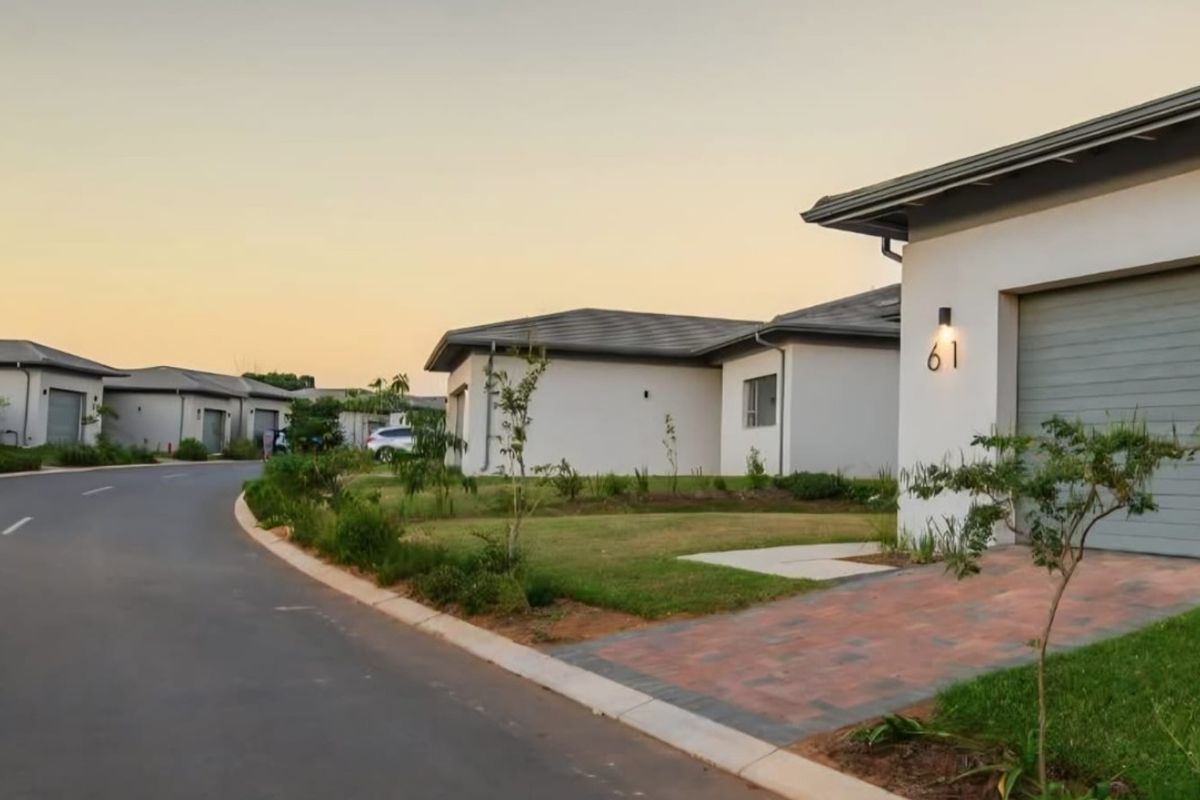 A street-level view of a modern residential estate featuring paved driveways, garage access, and well-maintained landscaped surroundings.