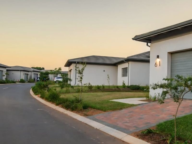 A street-level view of a modern residential estate featuring paved driveways, garage access, and well-maintained landscaped surroundings.