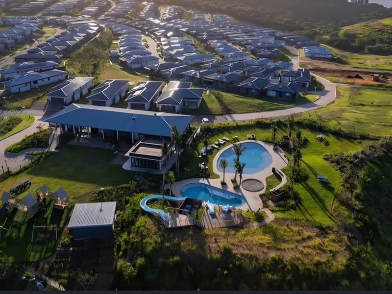 Aerial view of a residential estate featuring a clubhouse, swimming pools with water slides, and surrounding landscaped grounds.