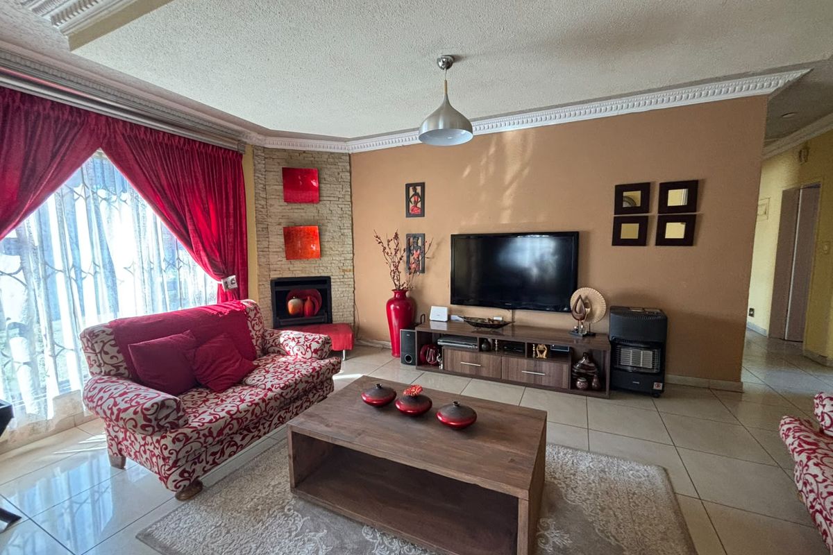 A living room featuring tiled flooring, a built-in fireplace with stone cladding, and decorative ceiling cornices.