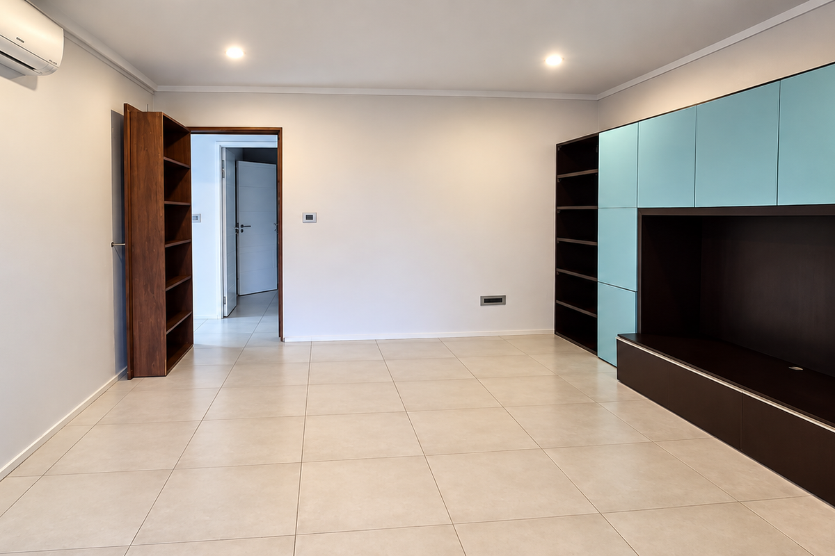 Spacious living area featuring neutral tiled flooring, recessed lighting, a wall-mounted air conditioning unit, and extensive built-in storage cabinetry.