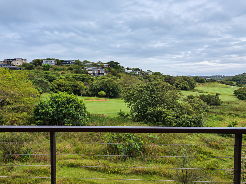 Scenic elevated view overlooking a lush green golf course and surrounding residential estate landscape.