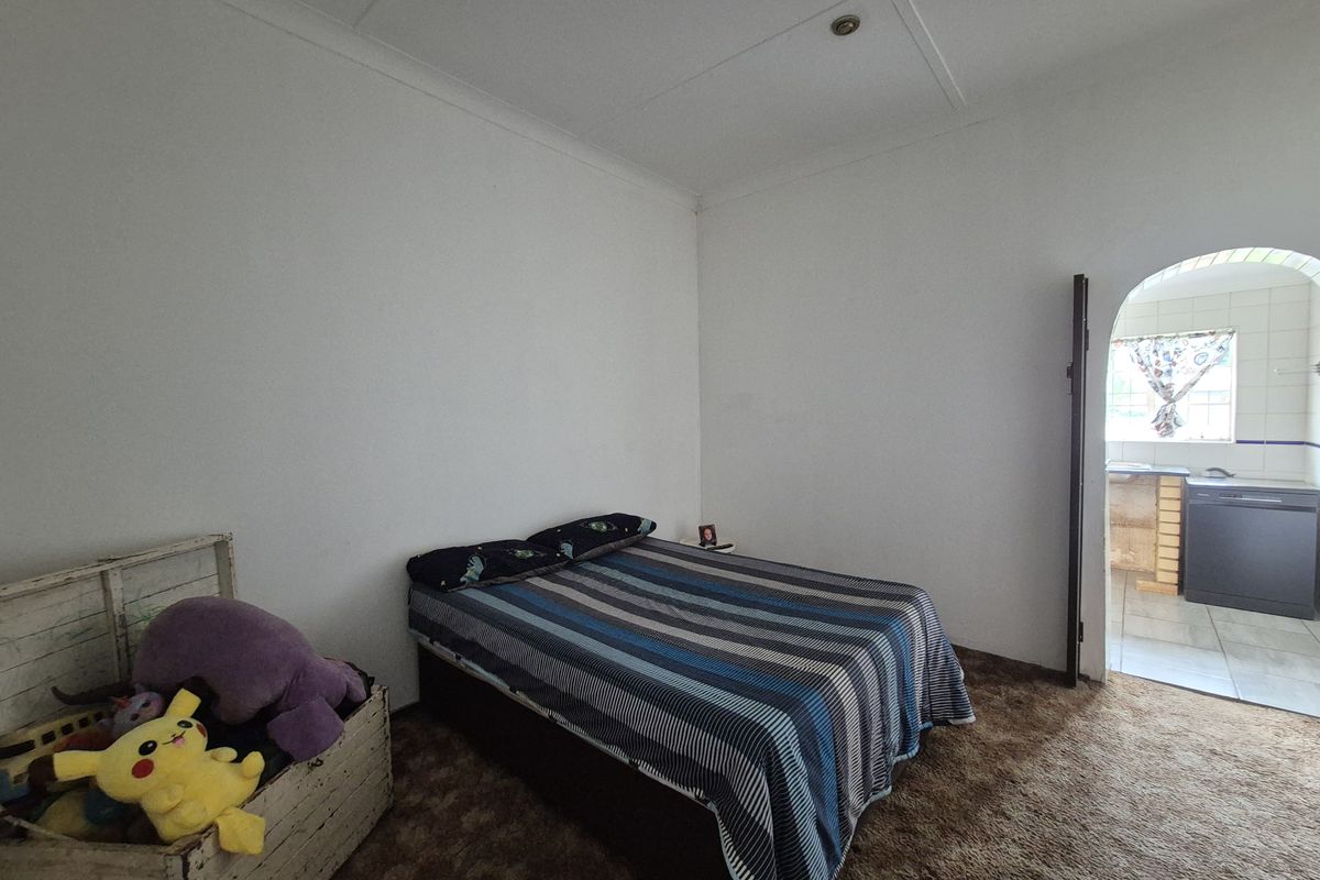 A bedroom featuring carpet flooring and an arched doorway leading to an adjacent tiled area.