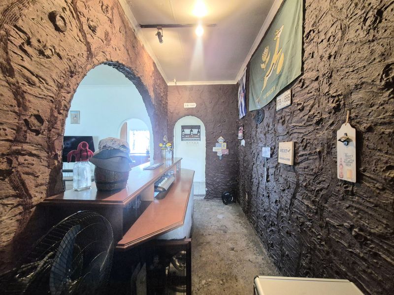 A dedicated bar area featuring unique textured walls, a built-in counter, and arched architectural details connecting to the adjacent living space.