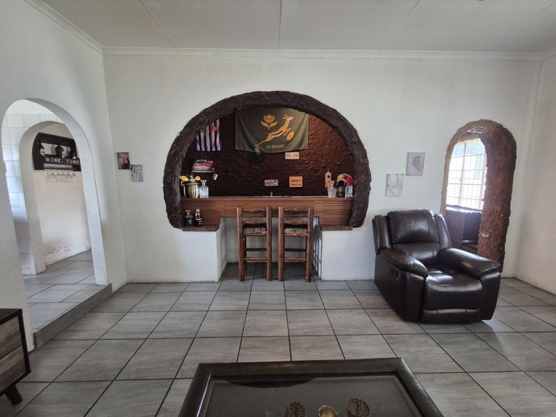 A dedicated bar area featuring a unique arched masonry surround, tiled flooring, and integrated counter space, providing a distinct entertainment zone within the home.