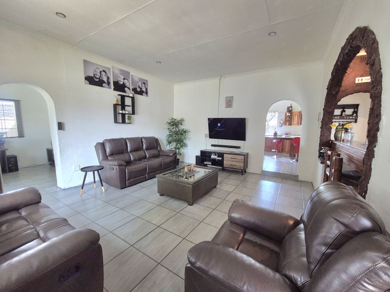 Spacious living room featuring tiled flooring, recessed lighting, and distinctive arched doorways leading to adjacent areas of the home.