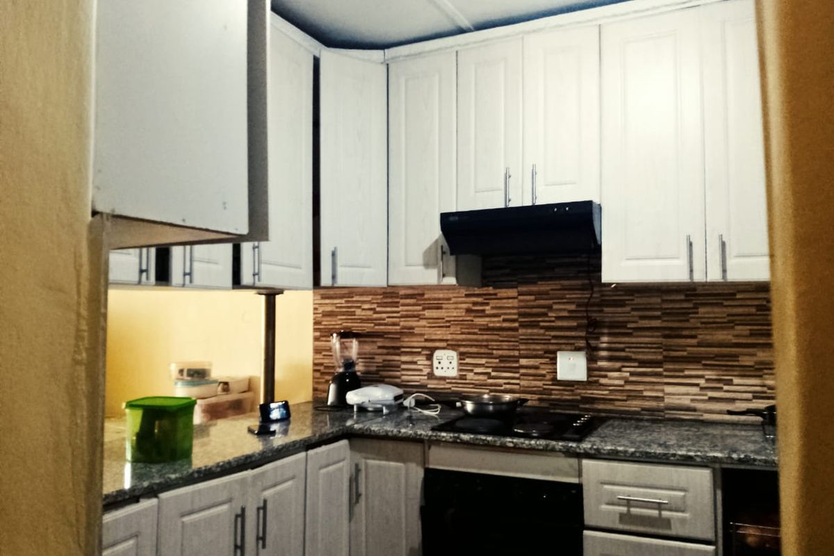 A functional kitchen featuring white cabinetry, granite countertops, a tiled backsplash, and built-in cooking appliances.