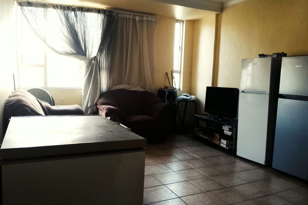 A living area featuring tiled flooring and large windows, currently in need of cosmetic updates to improve the overall aesthetic and brightness.