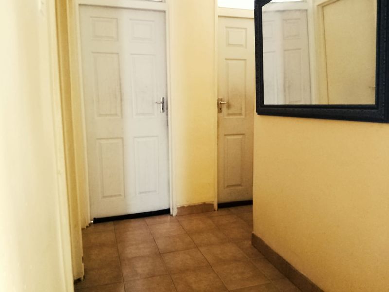 A functional hallway featuring tiled flooring and access to multiple internal rooms, showing signs of wear and requiring cosmetic updates.
