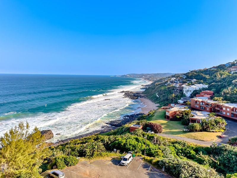 A scenic elevated view overlooking the coastline, ocean, and surrounding residential estate.