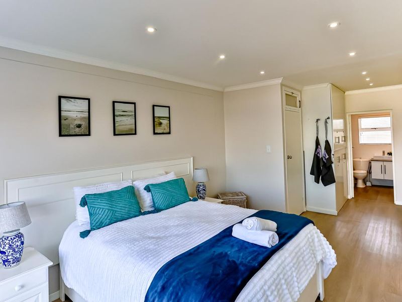 A well-maintained bedroom featuring laminate flooring, recessed downlighting, built-in cupboards, and direct access to an en-suite bathroom.