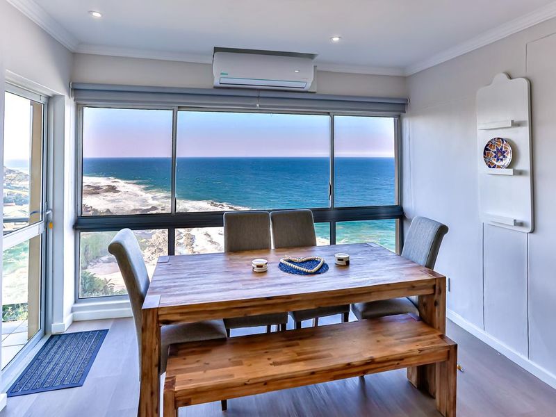 Bright dining area featuring large windows with panoramic ocean views, modern laminate flooring, and a wall-mounted air conditioning unit.