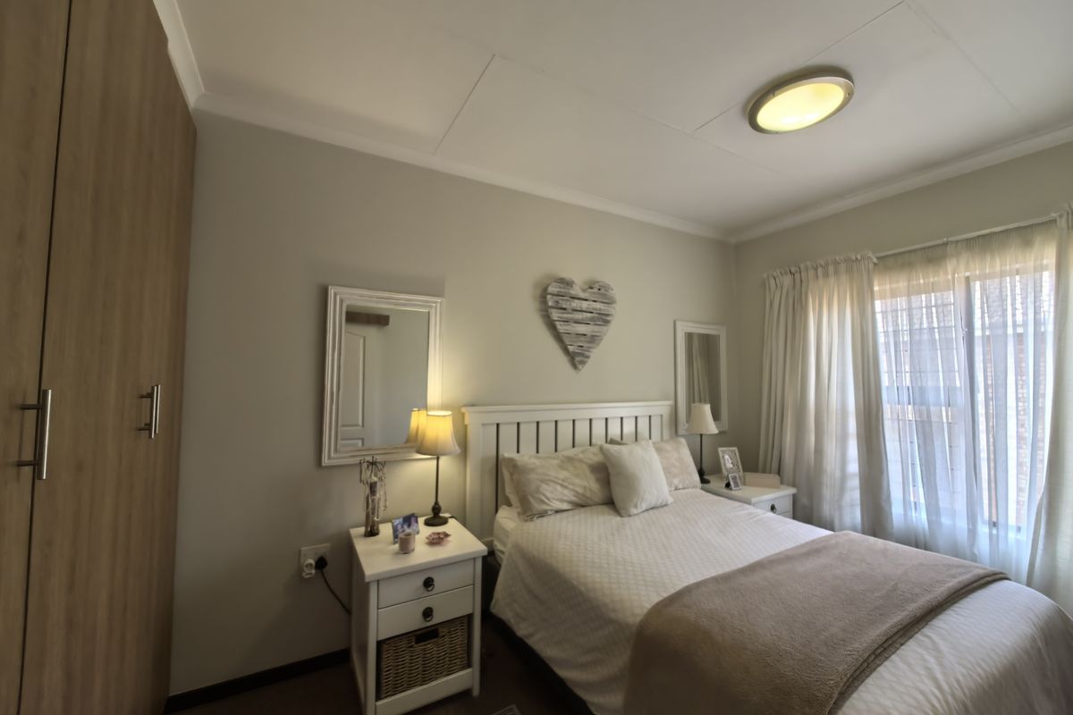 A cozy bedroom featuring a built-in wardrobe, neutral wall finishes, and natural light through window curtains.