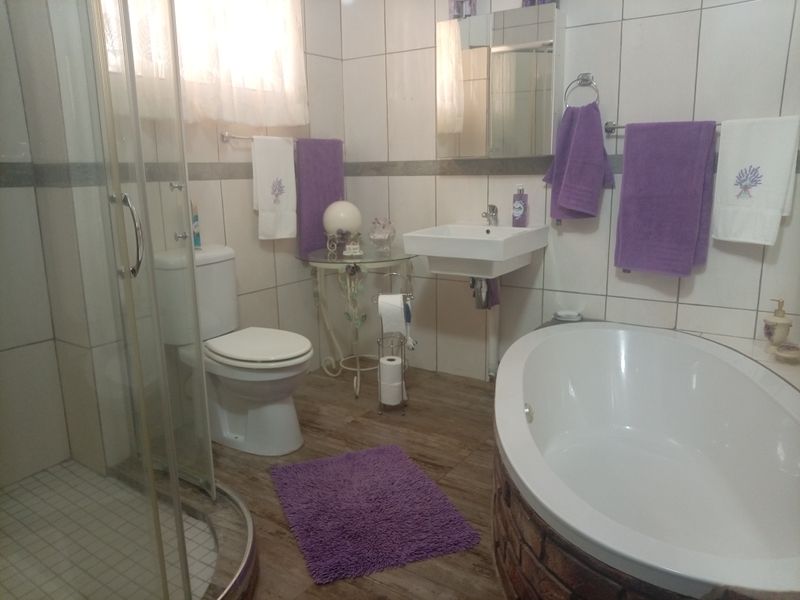 A functional bathroom featuring a separate shower enclosure, a built-in bathtub, a wall-mounted basin, and tiled finishes throughout.
