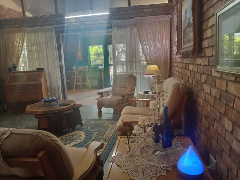A cozy living room featuring rustic exposed brick walls, a high vaulted ceiling, and large sliding glass doors that provide access to the outdoor area.