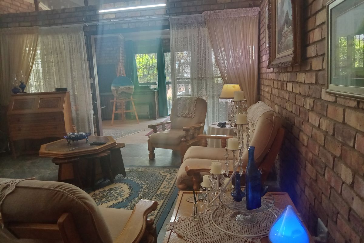 A cozy living room featuring rustic exposed brick walls, a high vaulted ceiling, and large sliding glass doors that provide access to the outdoor area.