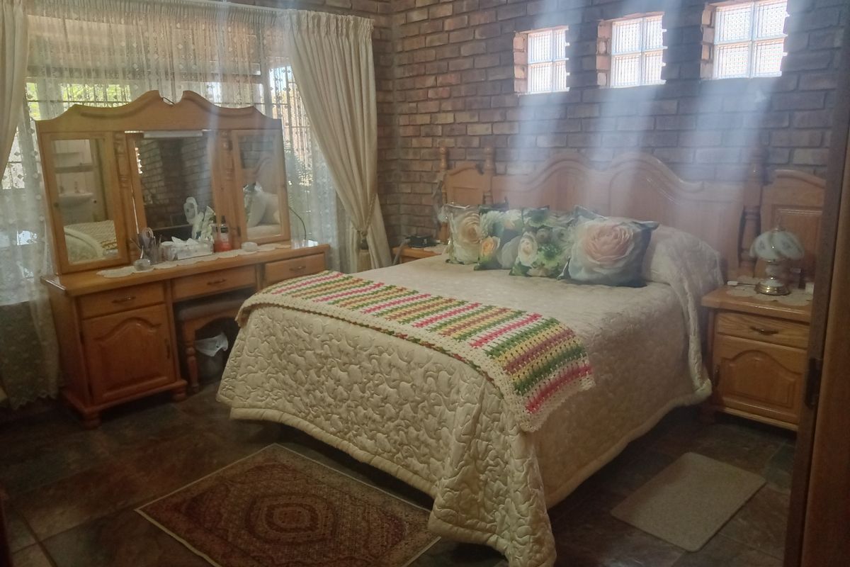 A bedroom featuring exposed brick walls, tiled flooring, and glass block accent windows, offering a rustic aesthetic.