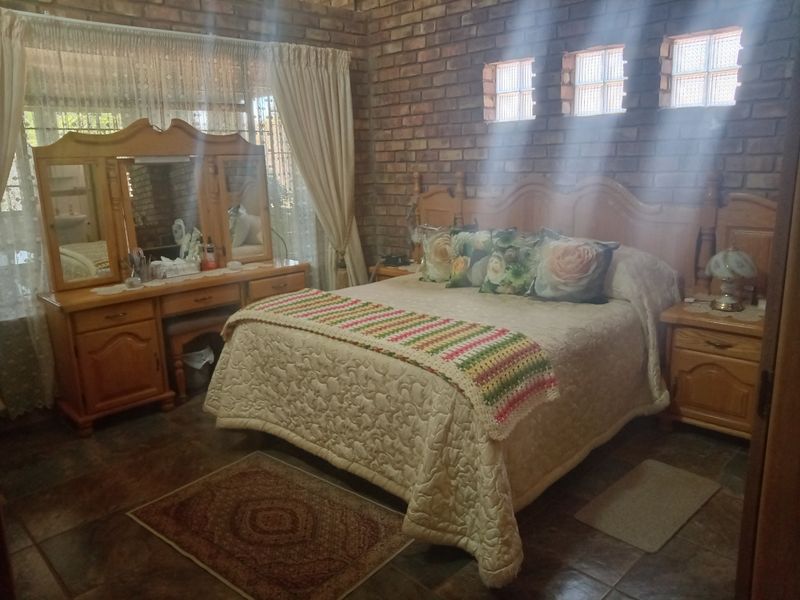 A bedroom featuring exposed brick walls, tiled flooring, and glass block accent windows, offering a rustic aesthetic.