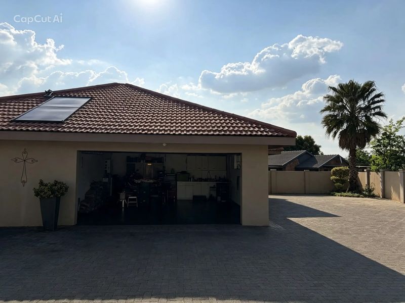 A spacious garage featuring a tiled roof with a solar panel, set against a paved driveway and secure boundary wall.