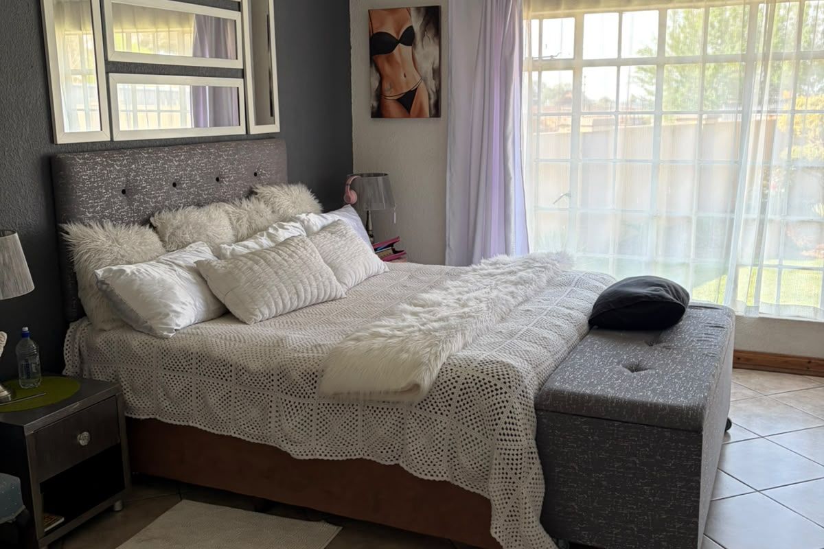 A bedroom featuring tiled flooring, large windows allowing natural light, and recessed ceiling lighting with crown molding details.