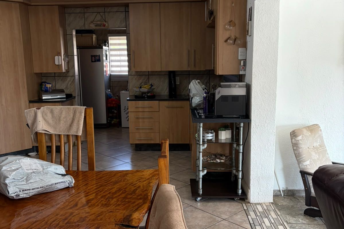 A functional kitchen featuring laminate cabinetry, stone countertops, and tiled flooring, with an adjacent scullery area for additional storage and preparation space.