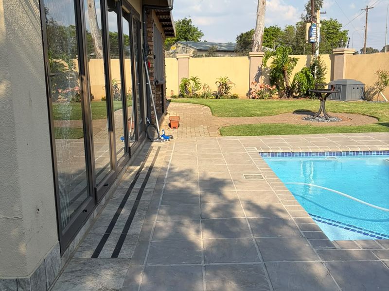 Outdoor pool area featuring a stone-tiled patio, swimming pool, and large sliding glass doors providing seamless access to the home interior.