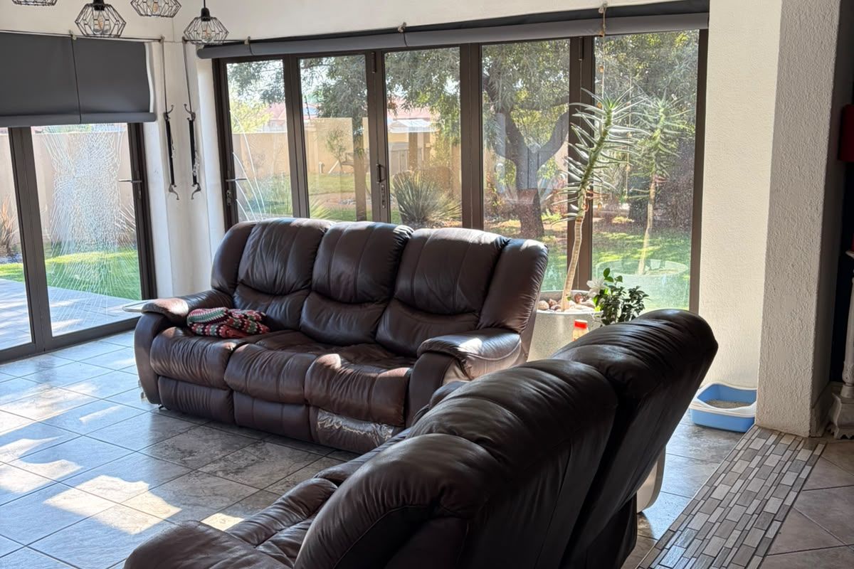 Spacious living area featuring large glass sliding doors with garden views, tiled flooring, and a unique timber beam light fixture.